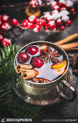 Mug of traditional mulled wine with cranberries, cinnamon sticks and anise star , close up