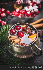 Mug of traditional mulled wine with cranberries, cinnamon sticks and anise star , close up