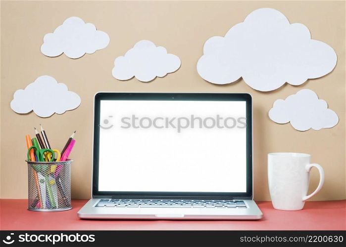 mug stationery near laptop clouds