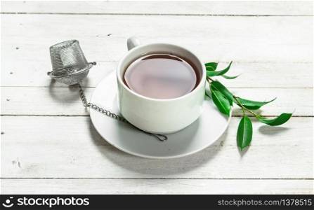 Mug with black tea. On a white wooden table.. Mug with black tea.