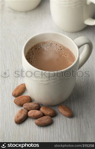Mug with hot chocolate milk and whole cocoa beans