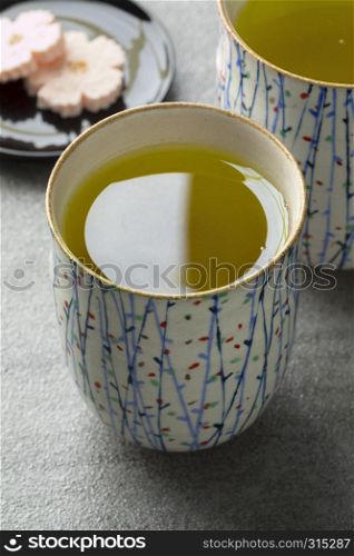 Mugs with traditional Japanese hot green tea and sweets