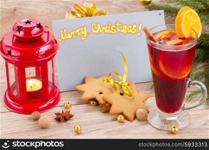 mulled red wine with christmascard on wooden background