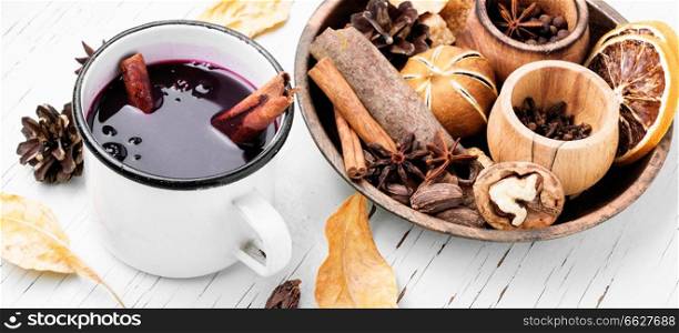 Mulled wine hot drink and spices in rustic mugs on rustic background. Seasonal warming drink mulled wine