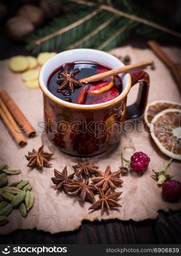 mulled wine in a brown ceramic cup on a brown sheet of paper with ingredients and spices