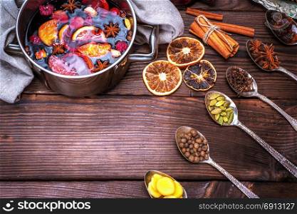 mulled wine in a saucepan and iron spoons with ingredients for the preparation of alcoholic beverages, empty space in the middle
