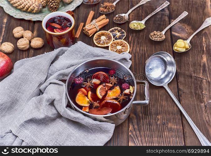 mulled wine in a saucepan and iron spoons with ingredients for the preparation of alcoholic beverages, top view