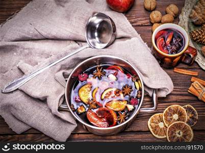 mulled wine in a saucepan on a brown wooden background, top view