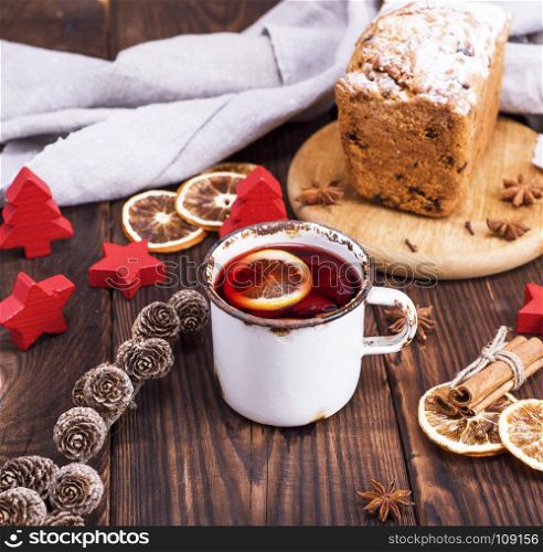 mulled wine in a white iron mug on a brown wooden background, top view