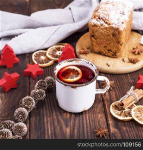 mulled wine in a white iron mug on a brown wooden background, top view