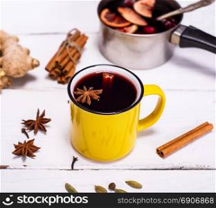 mulled wine in a yellow mug on a white wooden background, top view