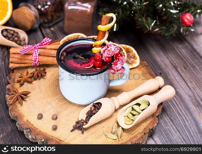 mulled wine in an iron mug and ingredients on a wooden background