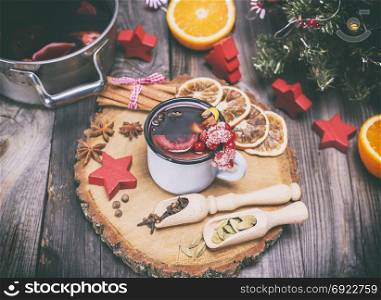 mulled wine in an iron mug and ingredients on a wooden background, vintage toning