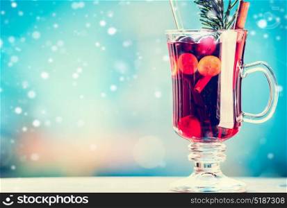 Mulled wine in cup with spices at winter day background with snow, front view, place for text