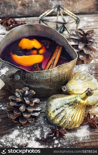 Mulled wine in old retro pan. The old pot of fragrant mulled wine on the background of Christmas decorations