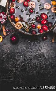 Mulled wine or punch in cooking pot on dark vintage background, top view, border