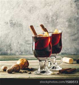Mulled wine with spices and orange slices on wooden table