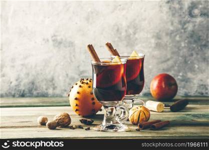 Mulled wine with spices and orange slices on wooden table. Glasses of delicious mulled wine on rustic table