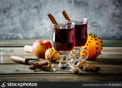 Mulled wine with spices and orange slices on wooden table. Mulled wine on rustic table