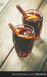 Mulled wine with spices and orange slices on wooden table. Space for text