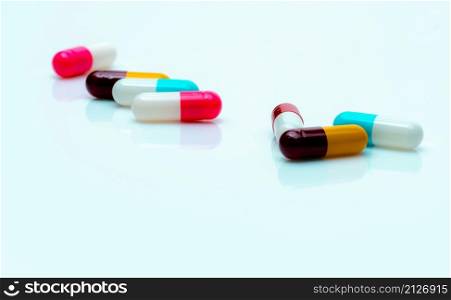 Multi-color antibiotic capsule pills spread on white background. Antibiotic drug resistance. Antimicrobial capsule pills. Pharmaceutical industry. Pink, white, blue, yellow, and red capsule pills.