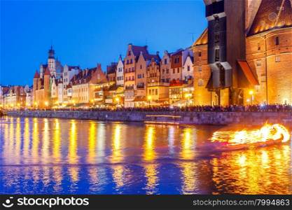 Multi-colored facades and boat on the central waterfront in Gdansk at night.. Gdansk. Central embankment at night.