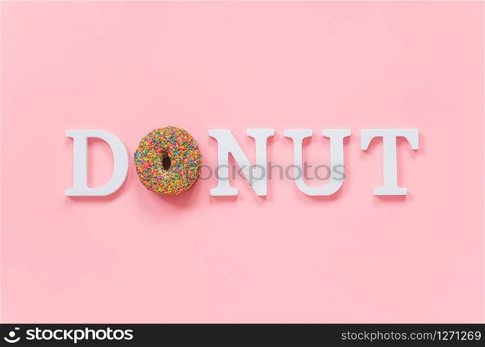 Multi colored glazed donut and white letters Donut on pink background. Top view Flat lay .. Multi colored glazed donut and white letters Donut on pink background. Top view Flat lay