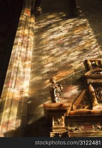 Multi-colored light from a stained glass window splashes over the wall and stonework in a chapel in St. Giles Cathedral in Edinburgh, Scotland.