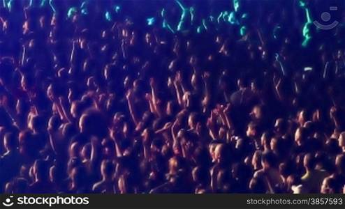 Multi-colored lights flashing across a crowd of cheering fans at a concert