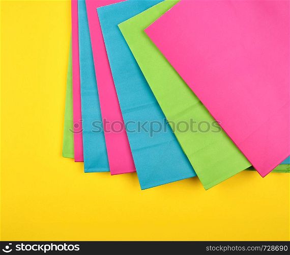 multi-colored paper shopping bags on a yellow background, flat lay