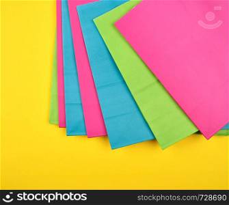 multi-colored paper shopping bags on a yellow background, flat lay