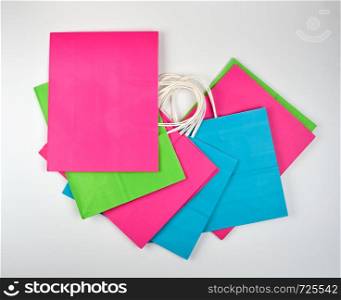 multi-colored paper shopping bags with white handles on a white background, flat lay