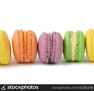 multi-colored round baked macarons cakes on a white isolated background, dessert stands in a row, close up