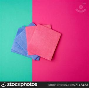 multi-colored square dishwashing sponges on a pink green background, top view, flat lay