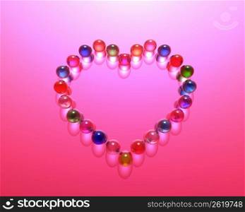Multi coloured pebbles in a heart shape on a pink background