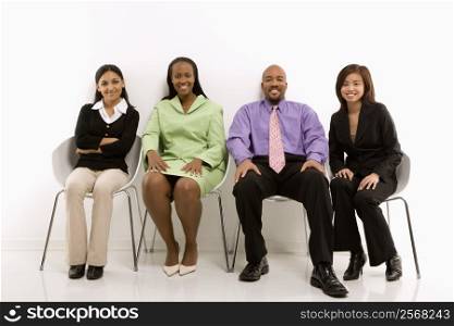 Multi-ethnic business group of men and women sitting and smiling at viewer.