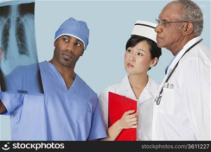 Multi ethnic doctors examining x-ray report over light blue background