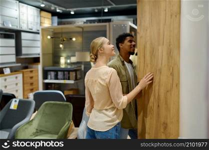 Multi-ethnic family couple buyer search wardrobe for new house apartment. Shopping in furniture shop. Multi-ethnic family couple searching wardrobe in shop