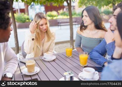 Multi-ethnic group of friends having a drink together in an outdoor bar. Young people having fun.. Multi-ethnic group of friends having a drink together in an outdoor bar.