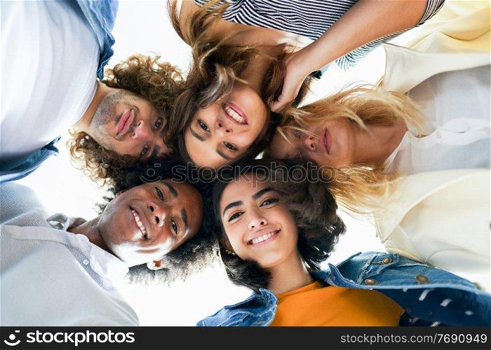 Multi-ethnic group of friends with their heads together in a circle outdoors. Multi-ethnic group of friends with their heads together in a circle.