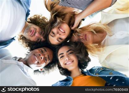 Multi-ethnic group of friends with their heads together in a circle outdoors. Multi-ethnic group of friends with their heads together in a circle.