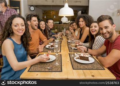 Multi-Ethnic Group of happy friends lunching and tasting the dessert at the restaurant