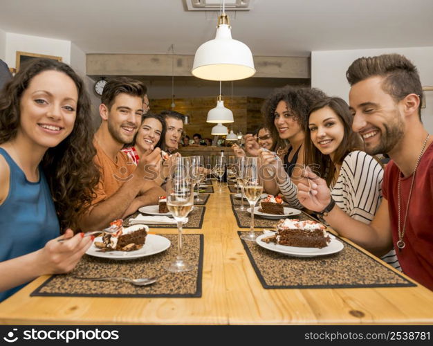 Multi-Ethnic Group of happy friends lunching and tasting the dessert at the restaurant