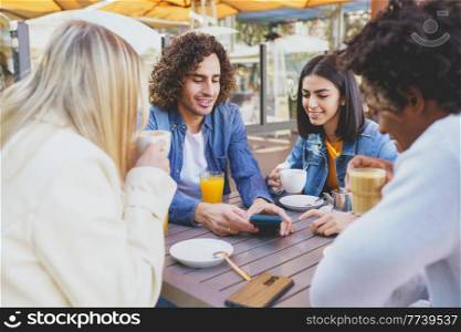 Multi-ethnic group of students having a drink on the terrace of a street bar. Young people having fun together. Multi-ethnic group of students having a drink on the terrace of a street bar.