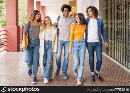 Multi-ethnic group of students walking together on the street while chatting and having fun.. Multi-ethnic group of students walking together on the street.