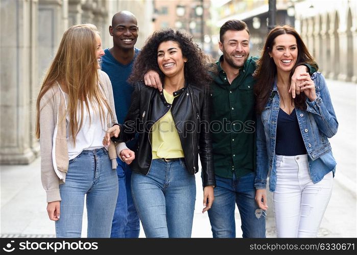 Multi-ethnic group of young people having fun together outdoors in urban background. group of people walking together