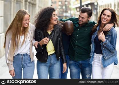 Multi-ethnic group of young people having fun together outdoors in urban background. group of people walking together
