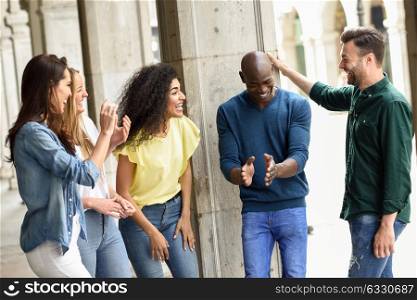 Multi-ethnic group of young people having fun together outdoors in urban background. group of people laughing together