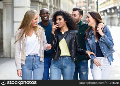 Multi-ethnic group of young people having fun together outdoors in urban background. group of people walking together pointing with the finger