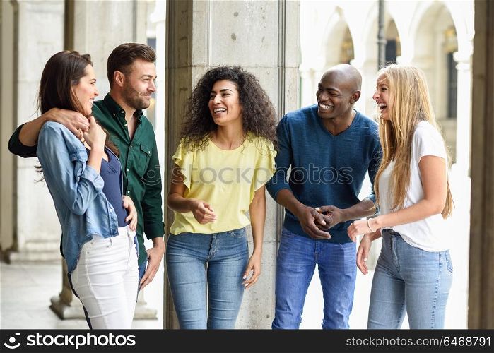 Multi-ethnic group of young people having fun together outdoors in urban background. group of beautiful women and men laughing together